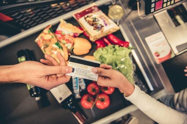 Pessoa entregando cartão de crédito para pagar compra em supermercado